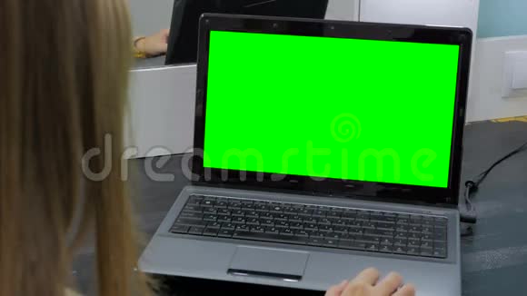 女人看着绿色屏幕的笔记本电脑视频的预览图