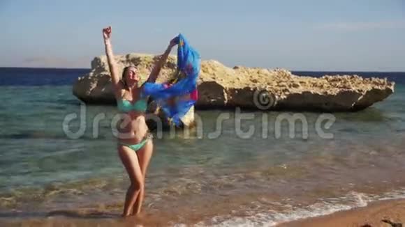 快乐女孩带着围巾在红海的夏季海滩散步慢动作视频的预览图