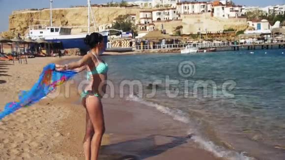 快乐女孩带着围巾在红海的夏季海滩散步慢动作视频的预览图