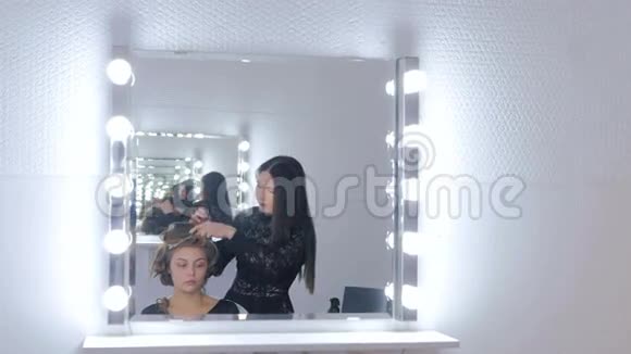 为留长发的年轻美女做发型的专业理发师视频的预览图
