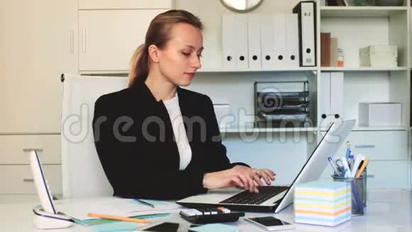 年轻的微笑女性在办公室的笔记本电脑里工作视频的预览图