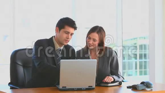 同事看着他们的笔记本电脑视频的预览图
