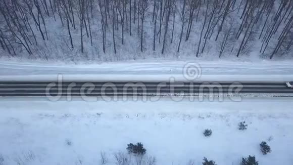 在冬季森林道路上驾驶汽车的鸟瞰图冬季景观视频的预览图