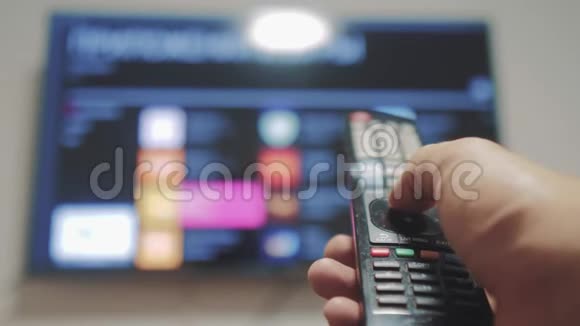 智能电视与应用程序和手男性手握遥控器关闭智能电视男人生活方式手控制电视视频的预览图