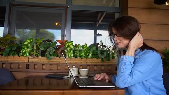 漂亮的女孩在咖啡馆里用笔记本电脑浏览视频的预览图