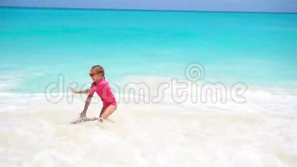 可爱的小女孩在海滩上在水里玩得很开心视频的预览图