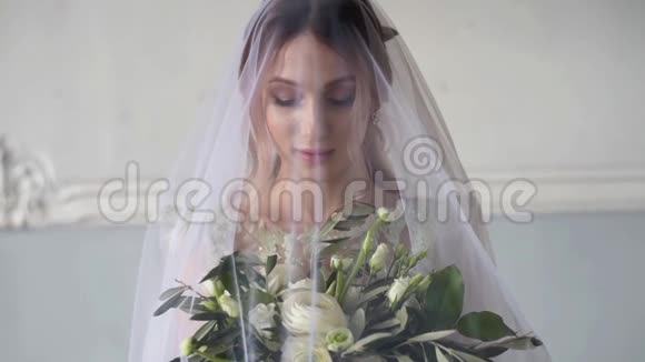 新娘穿着新娘礼服带着花束和蕾丝面纱视频的预览图
