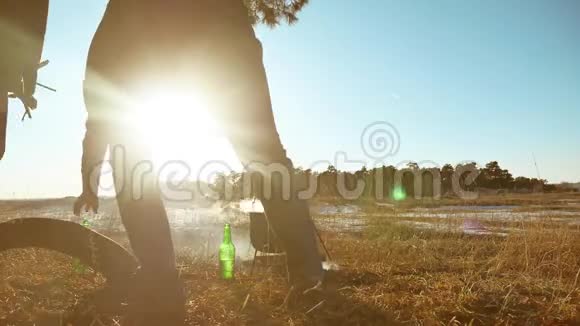 两名游客啤酒正坐在篝火徒步聚会上在大自然中露营剪影阳光日落两个剪影视频的预览图