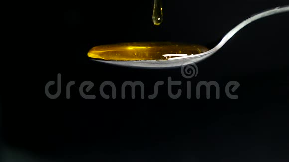黑背景下从勺子流出的蜂蜜视频的预览图