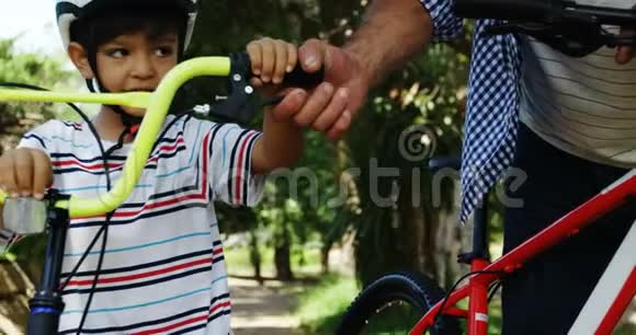父亲和儿子骑着自行车站在公园里视频的预览图