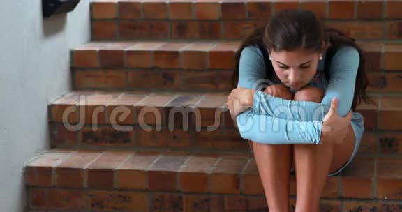 悲伤的女学生独自坐在楼梯上视频的预览图