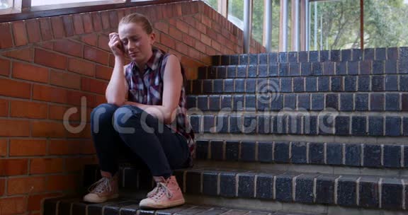 悲伤的女学生独自坐在楼梯上视频的预览图