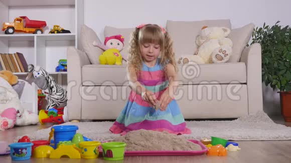 可爱的金发小女孩在工作室里玩沙子视频的预览图