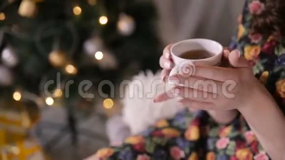 圣诞树附近有茶杯的女性手比迪女孩喝茶视频的预览图