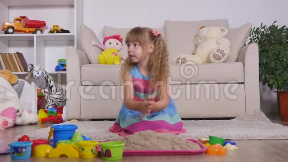 可爱的金发小女孩在工作室里玩沙子视频的预览图