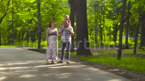 快乐的父母和小女孩在公园散步视频的预览图