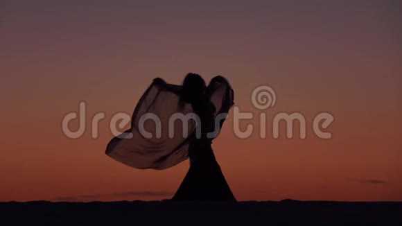 女孩优雅地在夕阳下用手纱跳舞剪影视频的预览图