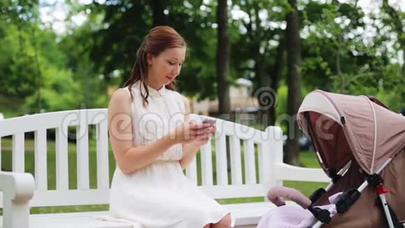 公园里有智能手机和婴儿车的快乐妈妈视频的预览图