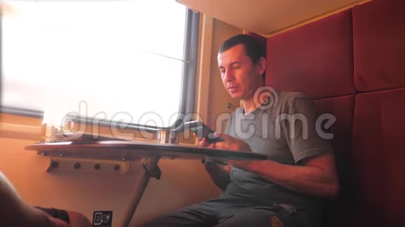 男人坐在火车车厢上手里拿着智能手机铁路喝着咖啡和茶慢生活方式慢生活方式视频的预览图