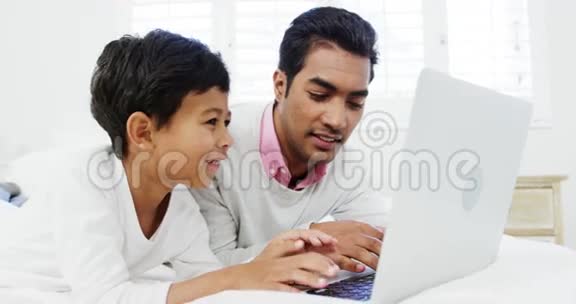 父子俩在床上用笔记本电脑视频的预览图