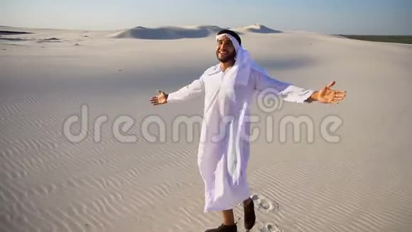 快乐的阿拉伯阿联酋酋长国男人走在白色沙漠中间在炎热的夏天享受生活视频的预览图