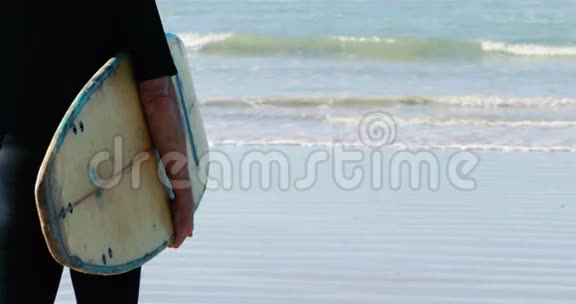有冲浪板的老人站在海滩上视频的预览图