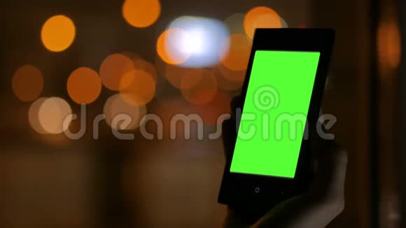 女人看着绿色屏幕的智能手机视频的预览图