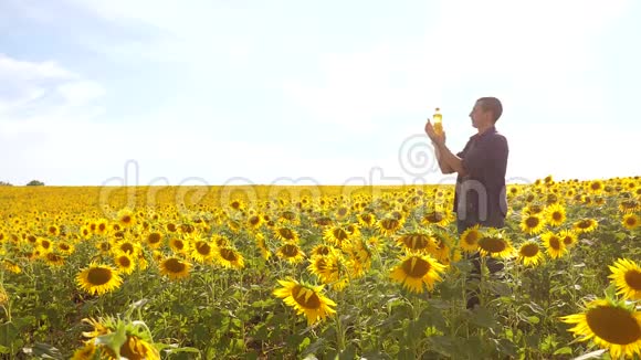 日落时分农夫手捧一瓶葵花籽油生活方式男人展示葵花籽油的生产视频的预览图