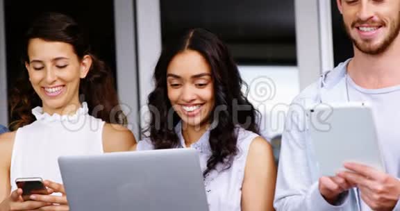 快乐的高管们使用数码平板电脑笔记本电脑和手机视频的预览图