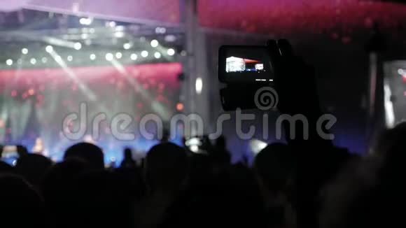 音乐音乐会上的人群车削的人群面前灯火辉煌多彩的舞台音乐会观众的剪影视频的预览图