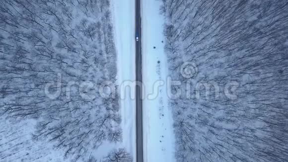 在冬季森林道路上驾驶汽车的鸟瞰图冬季景观视频的预览图