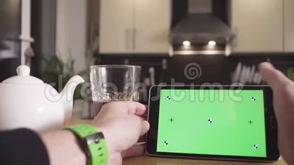 男性用手滚动带有绿色屏幕的平板电脑视频的预览图