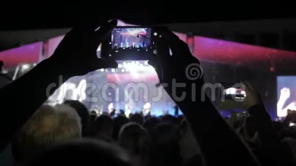 音乐音乐会上的人群车削的人群面前灯火辉煌多彩的舞台音乐会观众的剪影视频的预览图