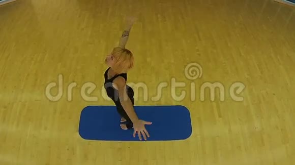 在体育馆的垫子上练习瑜伽的年轻女子视频的预览图