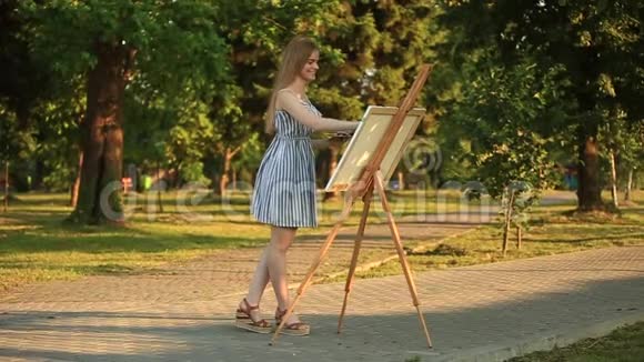 美丽的女孩在公园里用调色板画画视频的预览图