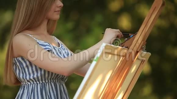 美丽的女孩在公园里用调色板画画视频的预览图