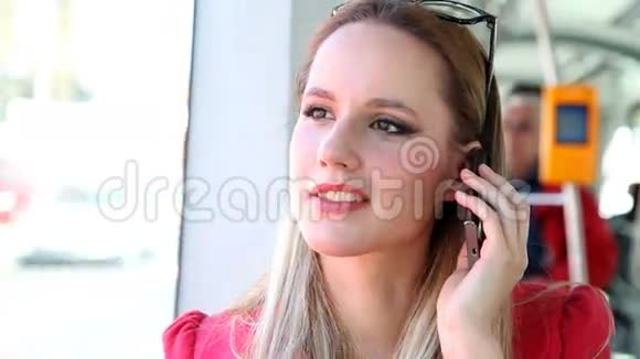 美丽的金发女郎乘电车用手机电话手机说话视频的预览图