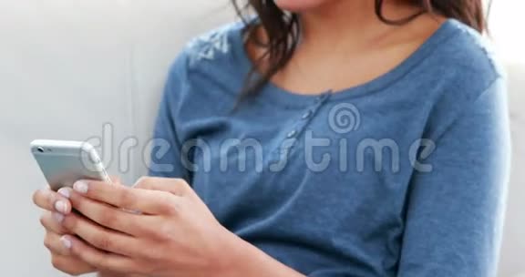 微笑的女人在沙发上发短信视频的预览图