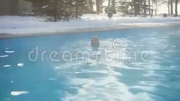 年轻的金发女子在冬天的室外游泳池游泳视频的预览图