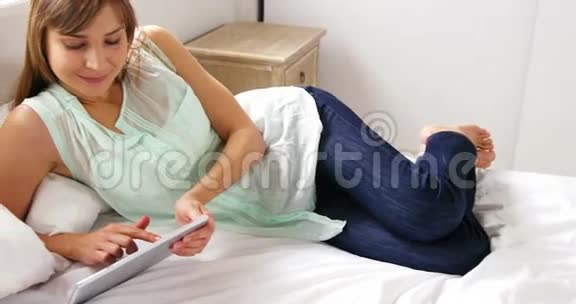 女人用平板电脑躺在床上视频的预览图