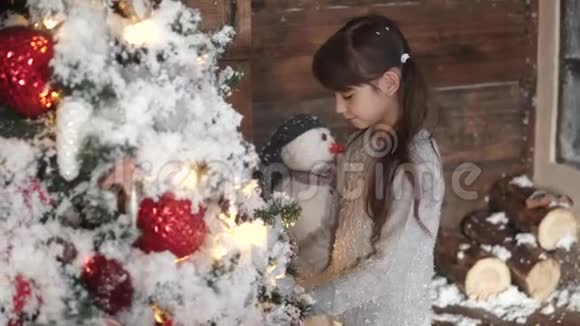 圣诞节或新年一个小女孩在圣诞树上挂装饰品假日感觉视频的预览图