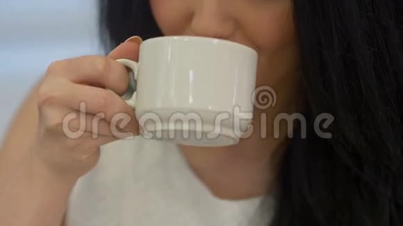 年轻的女人喝着茶微笑着视频的预览图
