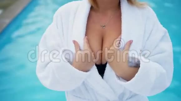 冬季室外游泳池附近穿浴袍的年轻金发女子视频的预览图