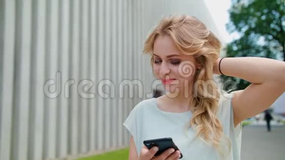 一位美丽的年轻女士在户外使用手机视频的预览图