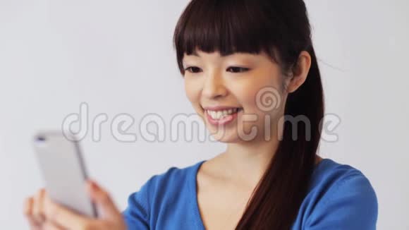 带着智能手机的快乐微笑的亚洲女人视频的预览图