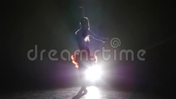 在演播室里跳桑巴舞的漂亮女孩在黑暗的背景烟雾剪影中视频的预览图