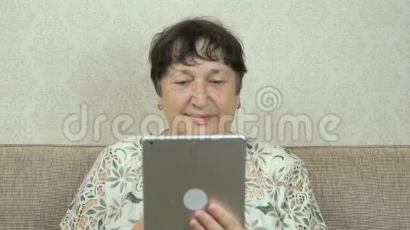 手持银色数码平板电脑的老年妇女视频的预览图