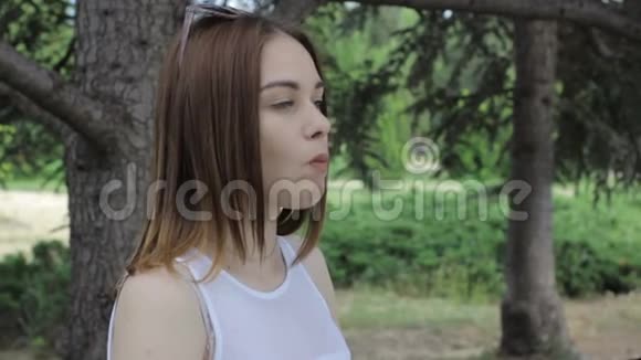年轻漂亮的女孩嚼口香糖户外视频的预览图