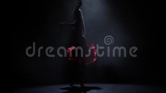 跳舞的女孩轮廓与烟雾在黑暗的背景慢动作视频的预览图
