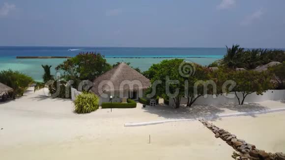 带白色沙滩棕榈树和绿松石印度洋的热带岛屿度假酒店的水疗平房的鸟瞰图视频的预览图